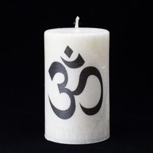 biela sviečka so symbolom mantry pokoja a jednoty